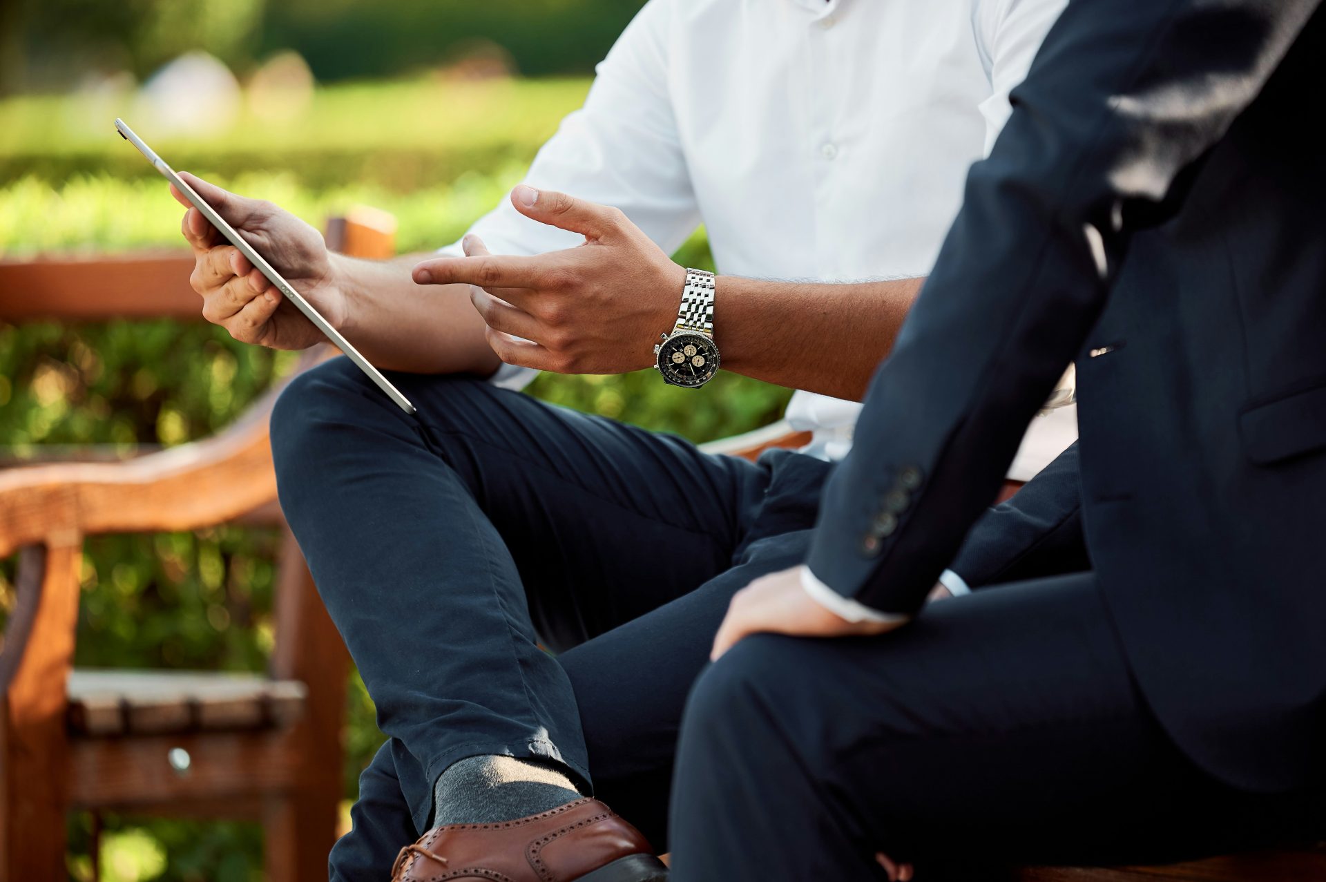 Two men discussing content on tablet outdoors.