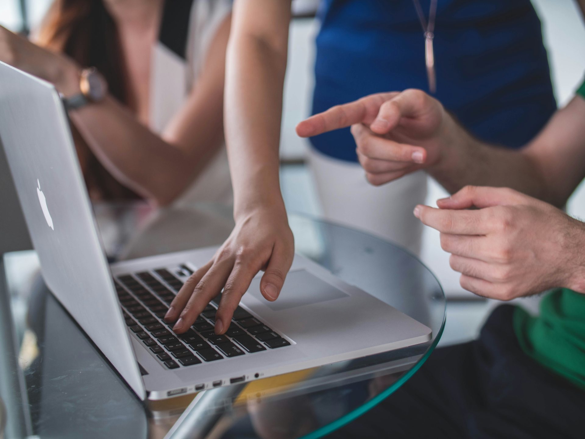 Hands pointing and typing on shared laptop.